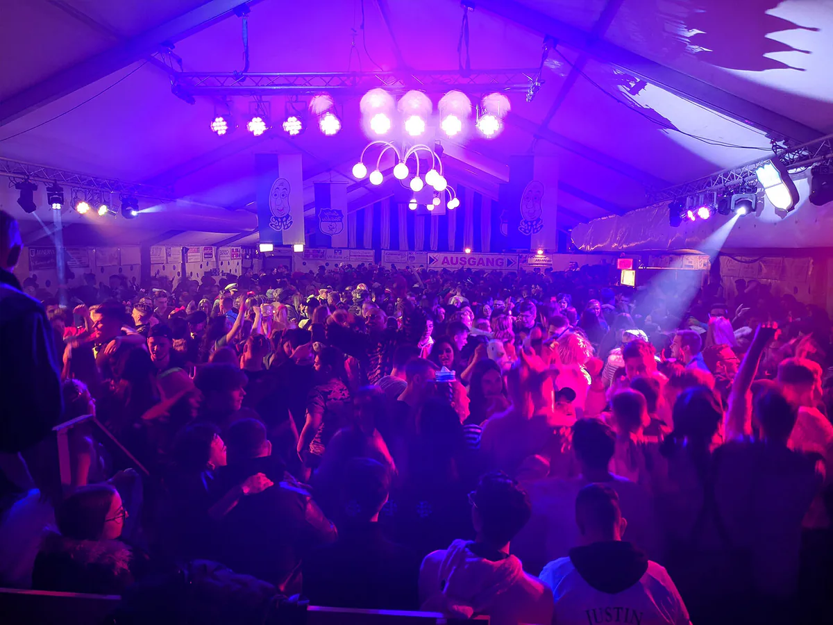Packed festival tent dance floor in purple light