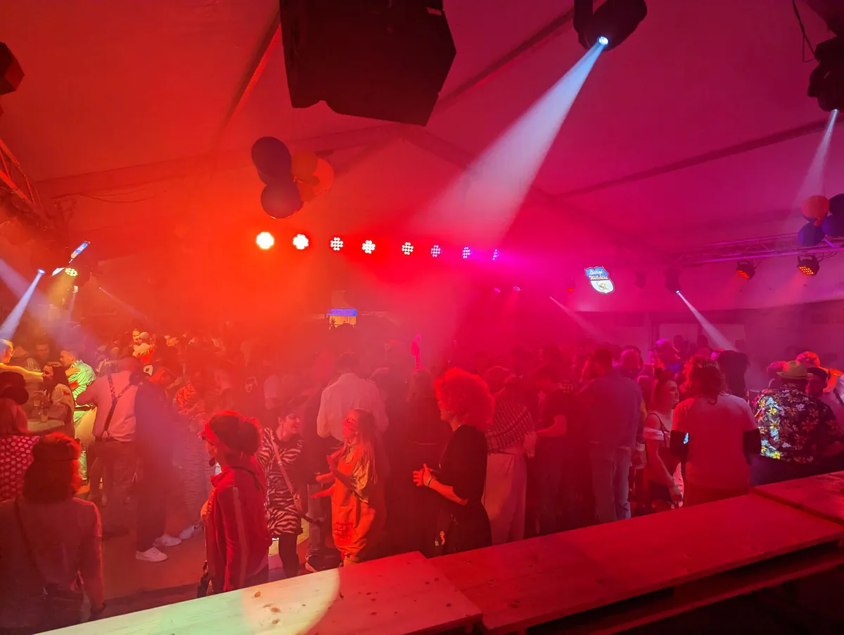 Crowd in a deep red lighting wash with spot beams